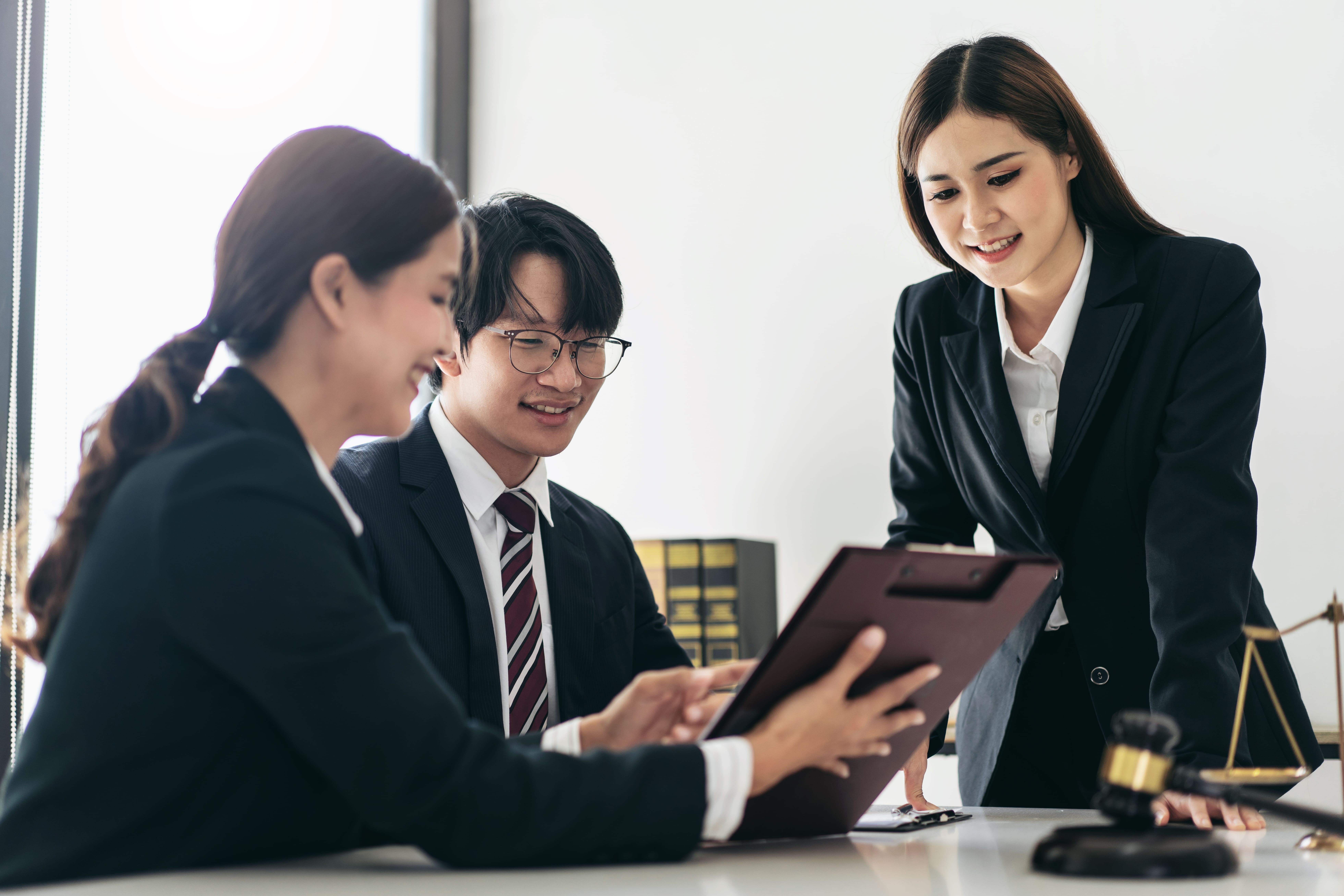 Despacho de abogados en San Vicente de la Barquera, reunión de abogados con cliente revisando documentos legales en una mesa de oficina