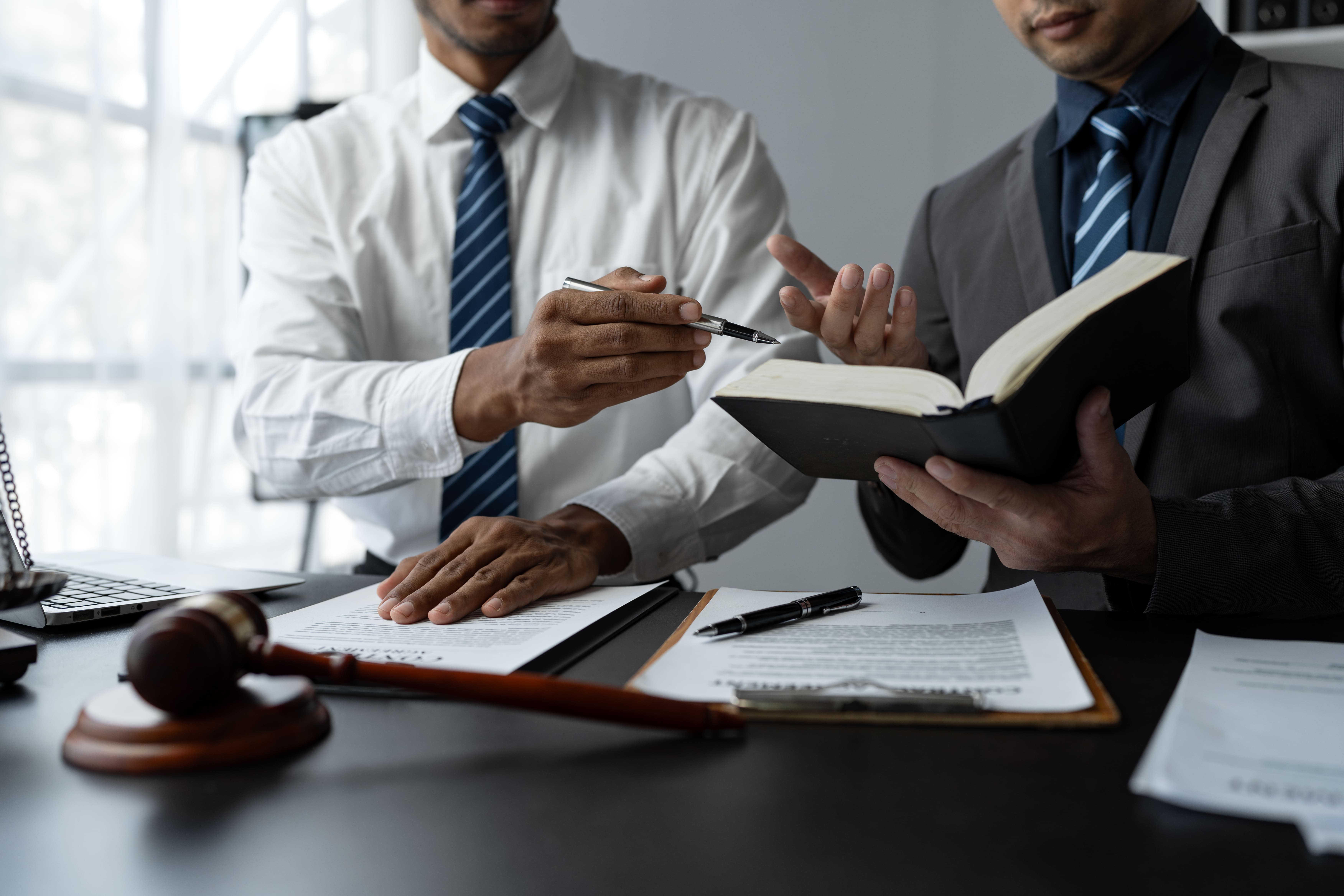 Abogado asesorando a un cliente en Cantabria durante la primera consulta, con documentos legales y ordenador portátil sobre la mesa
